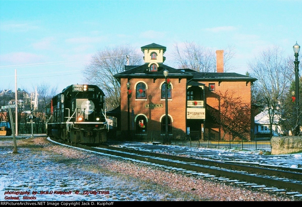 IC, Illinois Central SD70 1002 leads a westbound past the historic Victorian era station at Galena, Illinois. December 8, 1998. 